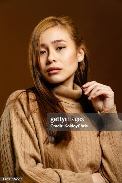 a young asian long-haired model posing in a studio shot with her arm slightly raised - asian woman beauty shot photos et images de collection