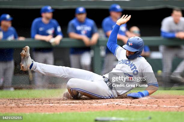 Lourdes Gurriel Jr. #13 of the Toronto Blue Jays slides into home plate and scores in the ninth inning against the Baltimore Orioles at Oriole Park...