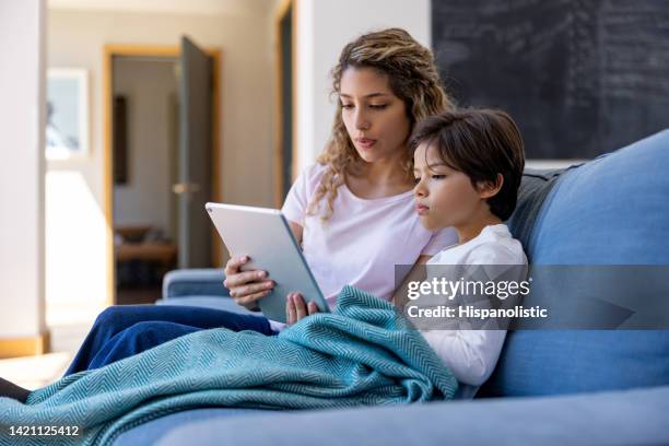 mutter und ihr kranker sohn sprechen mit dem arzt in einem videoanruf von zu hause aus - telemedizin stock-fotos und bilder