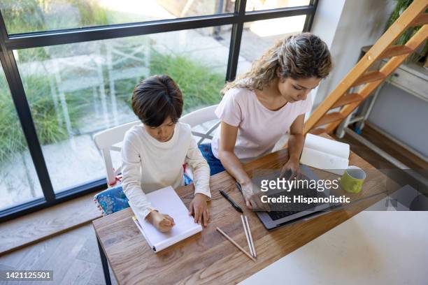 mother working at home while her son is doing his homework - stay home 個照片及圖片檔