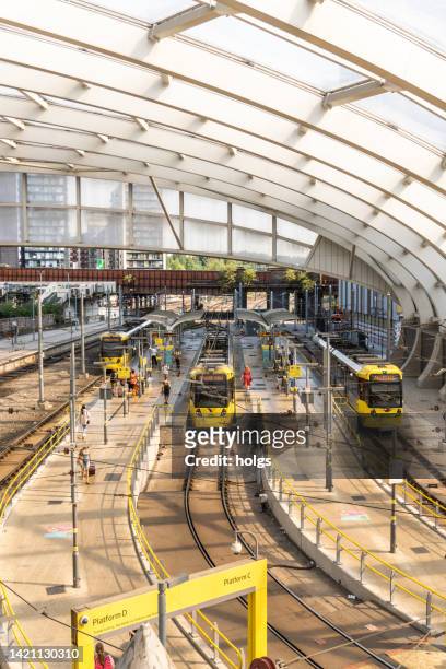 manchester united kingdom high angle view over the tram stop adjacent to the manchester victoria railway station with three yellow trams stopped. passengers can be seen on the platform. - victoria station manchester stock pictures, royalty-free photos & images