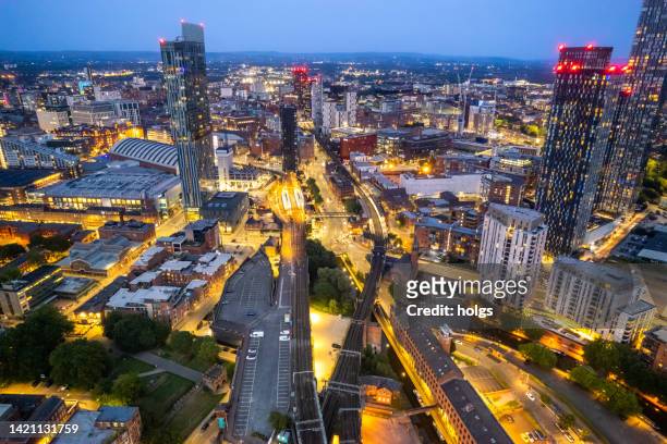 manchester united kingdom aerial shot of modern buildings with lots of counstruction in the central area of the city with historic canals and railways in the foreground by night - aerial view of manchester stock pictures, royalty-free photos & images