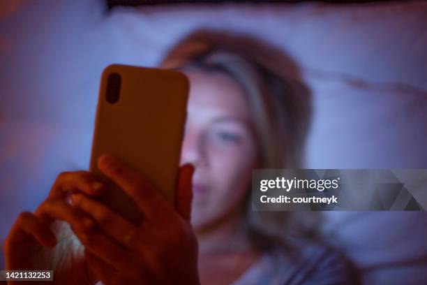 defocussed image of woman looking at a mobile phone in bed at night. - bokeh love bildbanksfoton och bilder