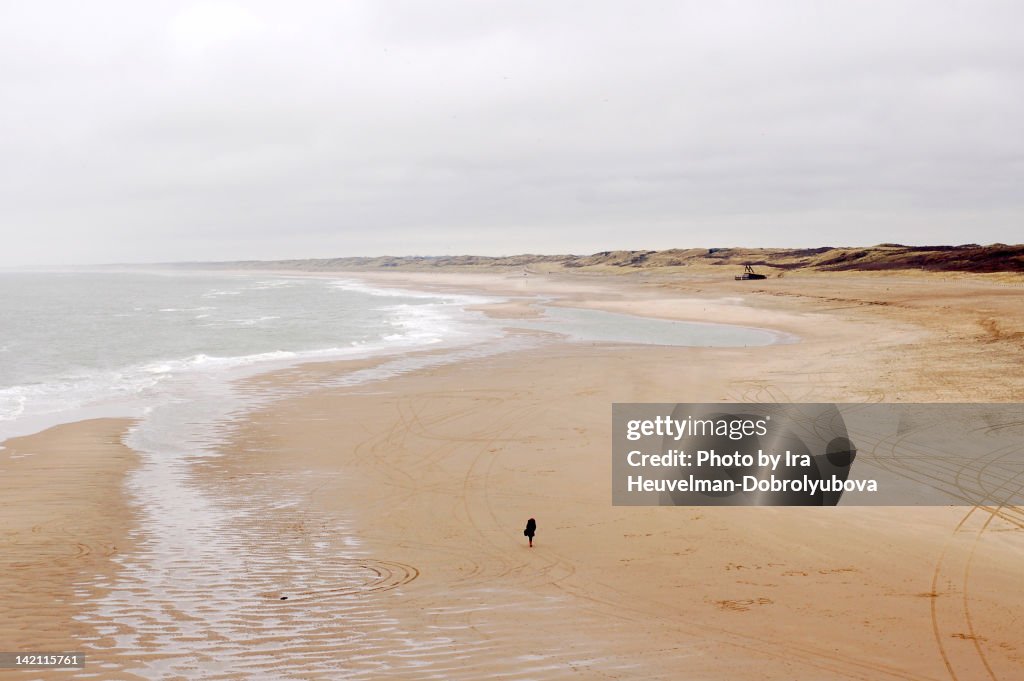 Lonely figure walking on empty beach