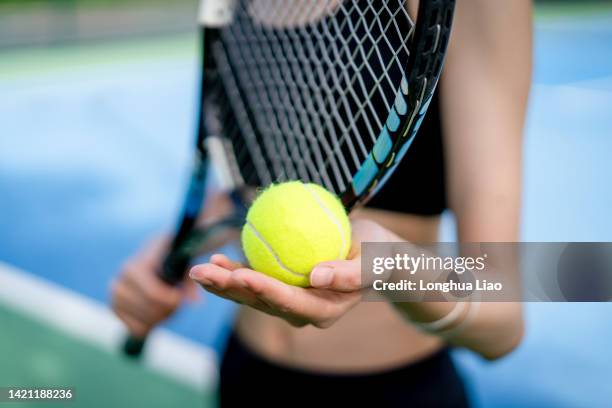 a female hand holds a tennis ball and racquet - exercise ball stock-fotos und bilder