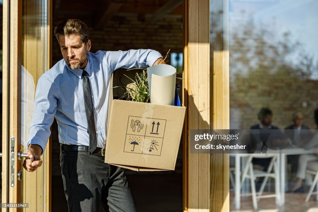 Depressed businessman leaving the office after being fired from his job.