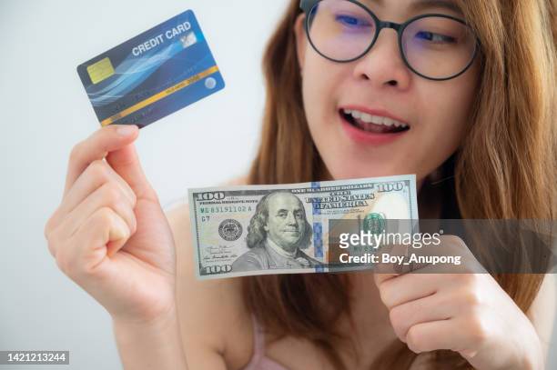 close up of woman holding cash and credit card in her hands. which one is better? - money borrow stockfoto's en -beelden