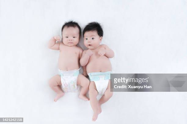 babies laying on bed - asian twins 個照片及圖片檔