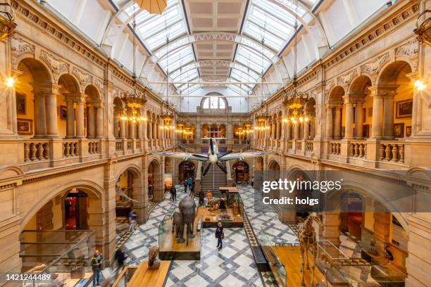 glasgow united kingdom interior view of the kelvingrove art galery and museum a free to enter for the public with people viewing the exhibits including a spitfire hanging in the room - museum exhibit stock pictures, royalty-free photos & images