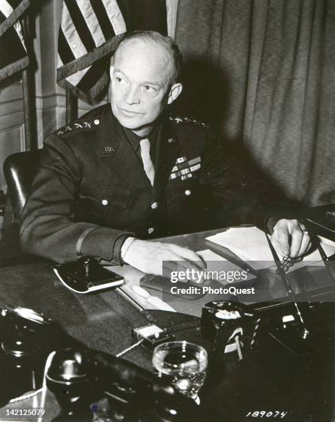 Portrait of American military commander General Dwight D. Eisenhower , Supreme Allied Commander during World War II, as he sits at a desk in the...