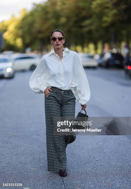 Nicole Mohrmann is seen wearing a black Saint Laurent vintage leather bag, SoSue white blouse, black and white meme pants, vintage black boots on...