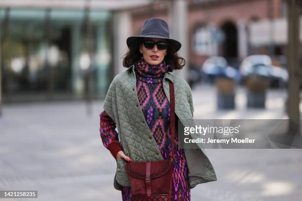 Nicole Mohrmann is seen wearing a red and purple long dress, SoSue khaki jacket, Saint Laurent red vintage bag, black Studio hat, vintage black boots...