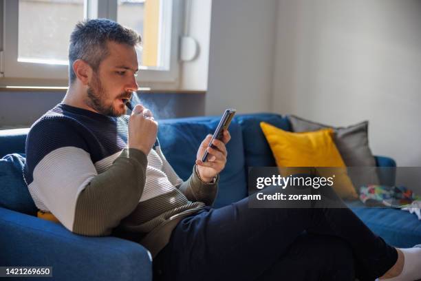 homme utilisant un téléphone intelligent et s’occupant des finances de la maison - shareholder photos et images de collection