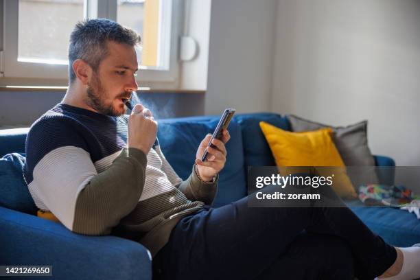 man using smart phone and taking care of home finances - world health organisation calls for regulation of ecigarettes stockfoto's en -beelden