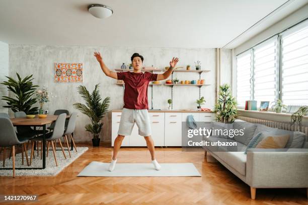 young man doing jumping jacks at home - star jump stock pictures, royalty-free photos & images