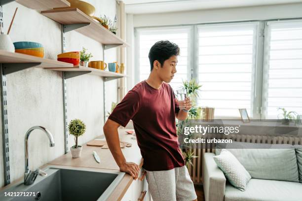 young man drinking water after exercising at home - man doing yoga in the morning stockfoto's en -beelden