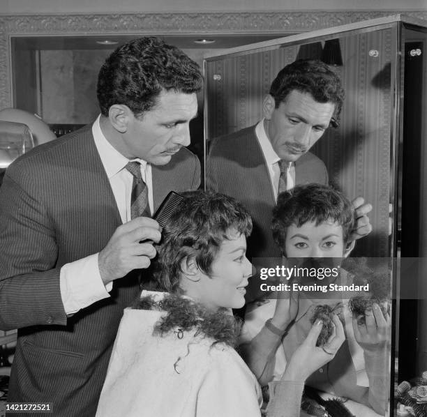 British actress Anne Heywood holding cuttings in her right hand as she has her hair cut by an hairdresser ahead of playing the title role in a stage...