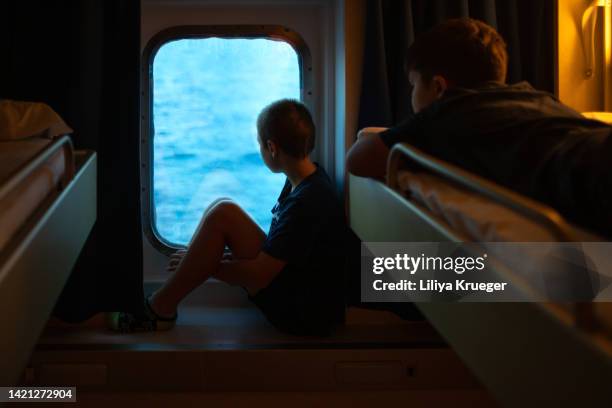a boy is sitting at the ship window. - ferry photos et images de collection