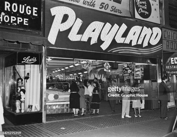 Patrons beneath the illuminated sign over the entrance to Playland on 42nd Street in New York City, New York, 1948. A neon sign in the entrance reads...