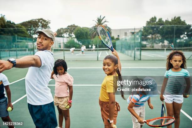 スポーツ、コーチ、子供たちが屋外コートでテニスをしている子供たちの試合のために練習しています。多様性、若者、ボールやラケットを持つプロの男性やメンターとのグループトレーニ� - tennis coaching ストックフォトと画像