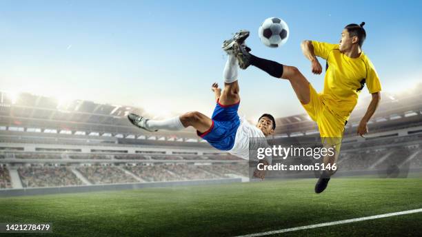 sportliche männer, fußballspieler kämpfen während des sportspiels über blauem, bewölktem himmelshintergrund im überfüllten 3d-stadion um den ball - sporttrikot freisteller stock-fotos und bilder
