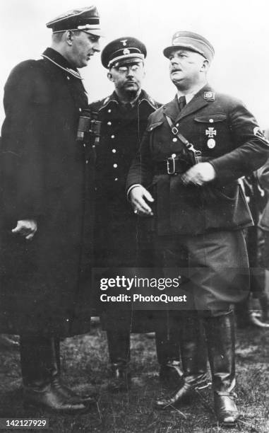 German Schutzstaffel Gruppenfuhrer Kurt Daluege speaks to Sturmabteilung commander Ernst Rohm , as SS commander Heinrich Himmler listens, Germany,...