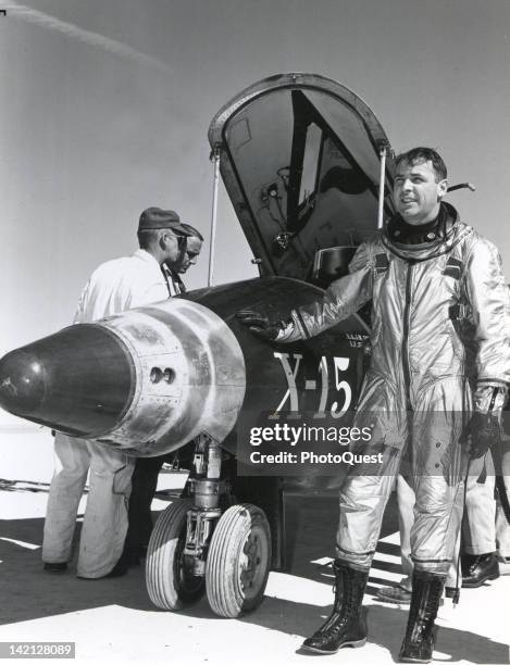 Portrait of American military test pilot Major Robert M. White as he poses with his hand on the North American X-15 experimental rocket plane at...