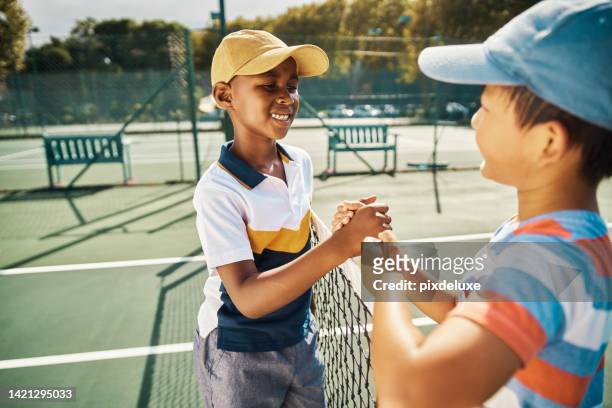 テニスの子供たちは、日当たりの良いスポーツクラブの屋外コートで試合、競争、楽しいゲームのために握手します。若い学校の友達、幸せな男の子と良いスポーツマンシップ、サポートと� - drive smile ストックフォトと画像