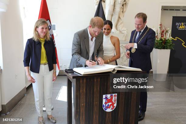 Prince Harry, Duke of Sussex and Meghan, Duchess of Sussex sign the golden book at the town hall during the Invictus Games Dusseldorf 2023 - One Year...
