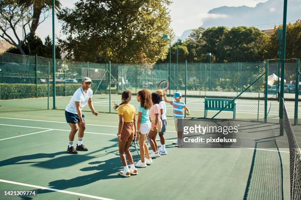 tennis sports teacher coaching children, students or kids on a tennis court for sport education. fitness, exercise and workout as coach teaching a training game to a young learning student class - sports training camp stock pictures, royalty-free photos & images