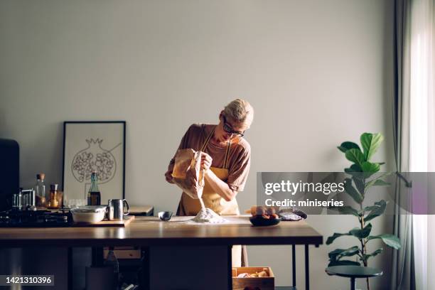 beautiful woman pouring flour on the work top in the kitchen at home - baking bread stock pictures, royalty-free photos & images