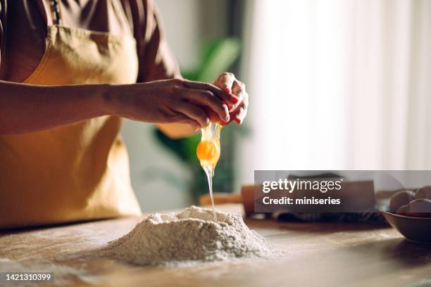 anonymous woman breaking eggs for the baking mixture - breaking bread stock pictures, royalty-free photos & images