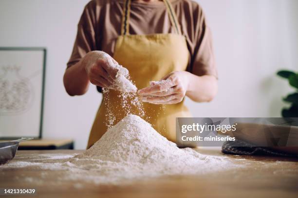 anonymous woman adding and preparing flour for kneading - kneading stock pictures, royalty-free photos & images