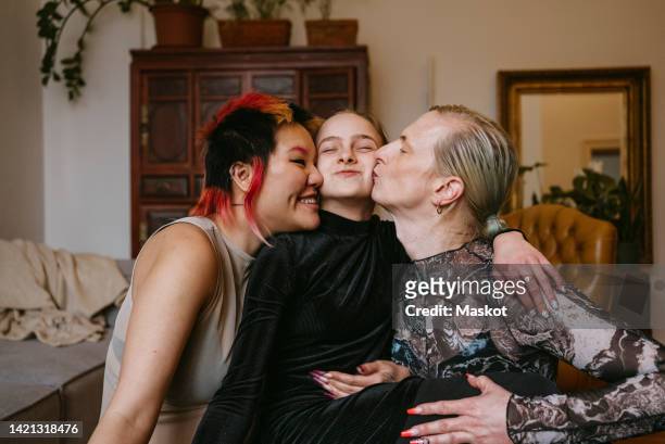 happy lgbtqia couple kissing daughter at home - lgbtq  and female domestic life fotografías e imágenes de stock