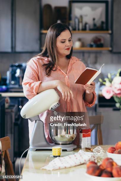 woman reading a recipe book - cooking cookbook stock pictures, royalty-free photos & images