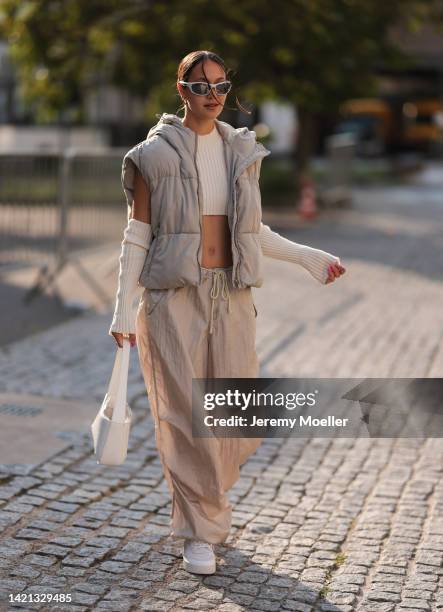 Sase Fu is seen wearing silver shades, white high neck knit crop top with matching knit gloves, a beige short puffer vest, beige parachute pants from...