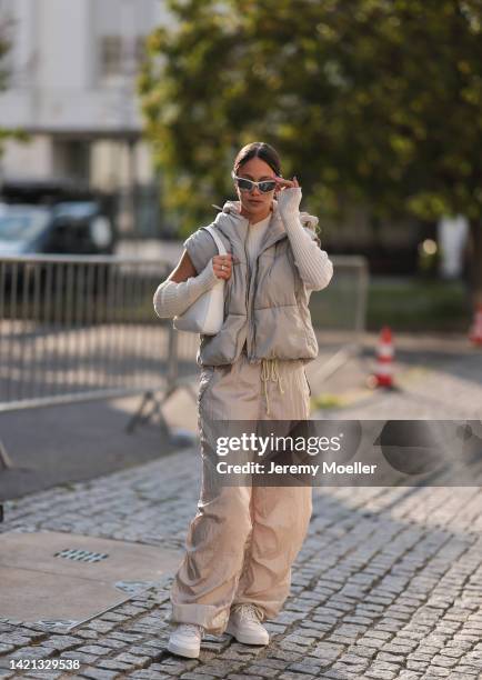 Sase Fu is seen wearing silver shades, white high neck knit crop top with matching knit gloves, a beige short puffer vest, beige parachute pants from...