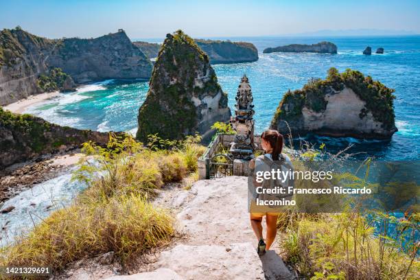 woman looking at diamond beach, nusa penida, indonesia - bali stock-fotos und bilder