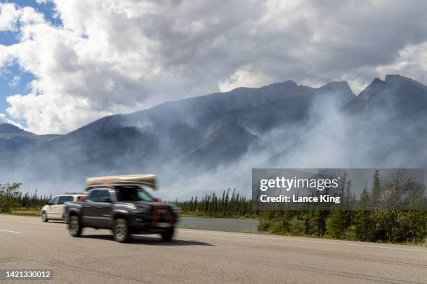 Vehicles pass by as smoke rises from the Chetamon Mountain wildfire on September 5, 2022 in Jasper National Park in Jasper, Alberta, Canada. ATCO,...