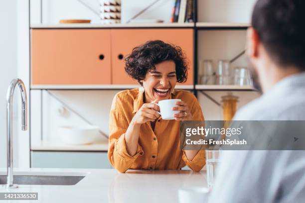 ein glückliches paar, das tee in der küche trinkt, redet und lacht - enjoying coffee stock-fotos und bilder
