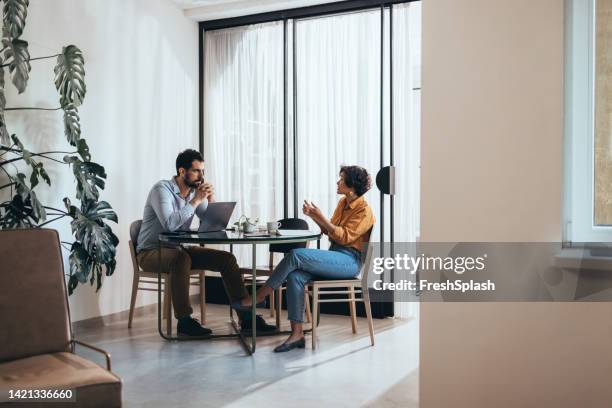 two colleagues cooperating and helping each other while sitting in the office - coach stockfoto's en -beelden