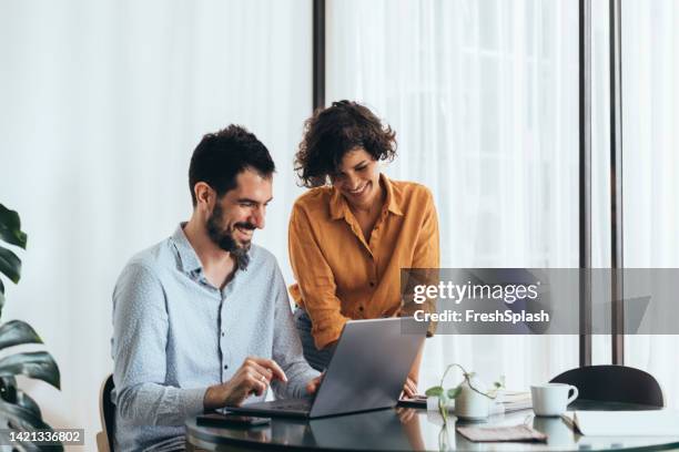 dos colegas felices cooperando en el trabajo - compañero de trabajo fotografías e imágenes de stock