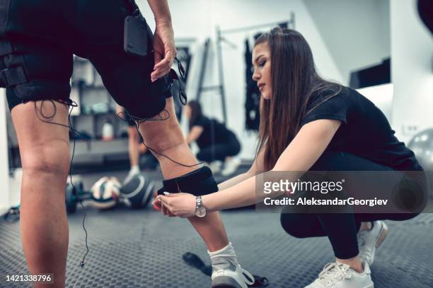 female getting ems bodysuit attached to legs before workout - female muscle calves stock pictures, royalty-free photos & images