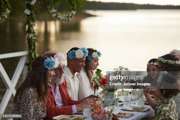 family having midsummer meal at lake - midsummer sweden stock-fotos und bilder