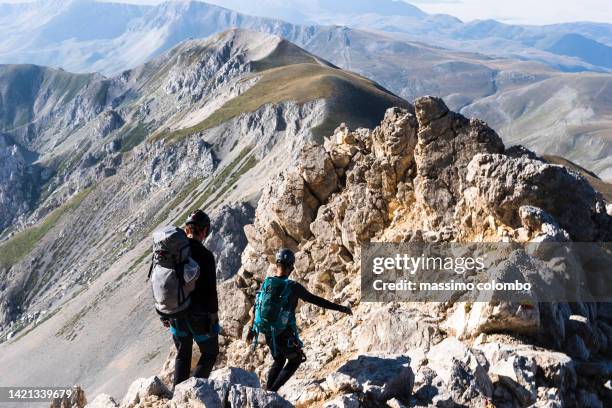 couple of climbers walking on the mountain ridge - parque nacional de abruzzo fotografías e imágenes de stock