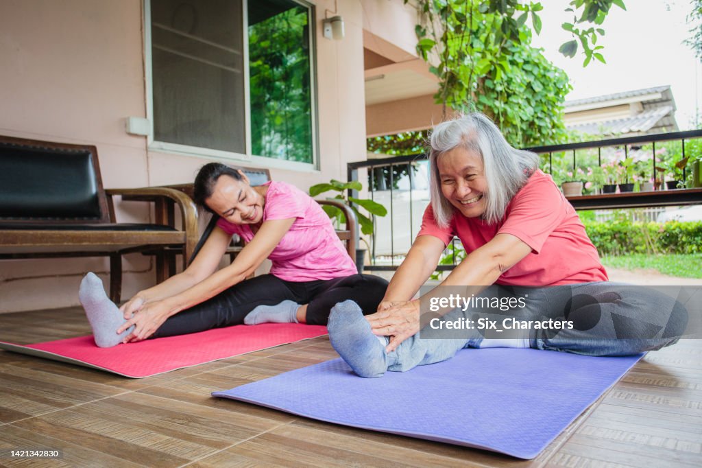 La mujer asiática mayor y los amigos maduros disfrutan haciendo ejercicio y entrenando yoga juntos en casa