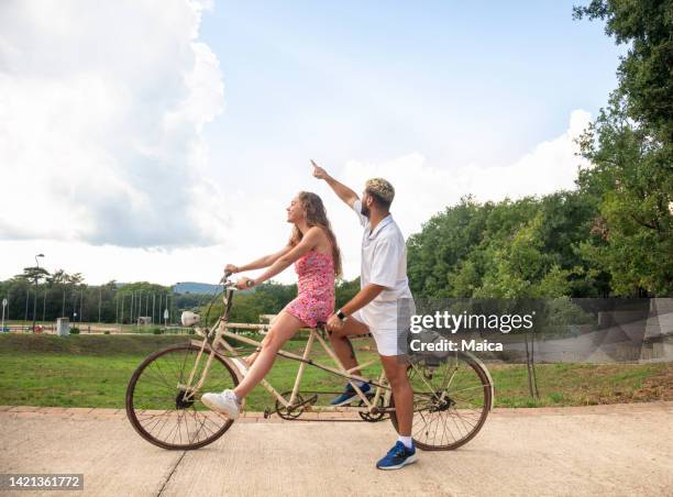 feliz pareja montando en bicicleta tándem - ciclismo tandem fotografías e imágenes de stock