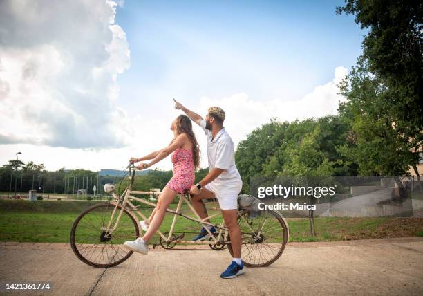 coppia felice in sella a una bicicletta tandem - tandem bicycle foto e immagini stock