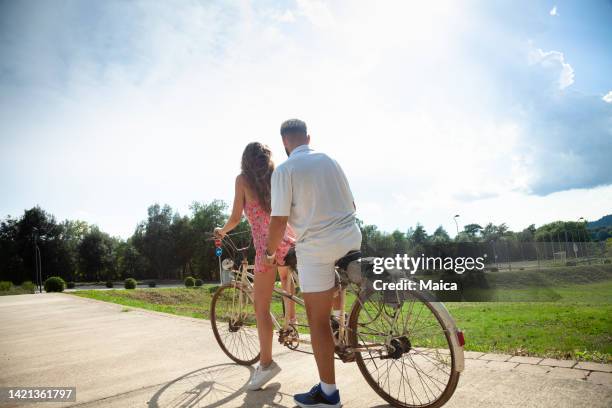 happy couple riding tandem bicycle - tandem bicycle stockfoto's en -beelden