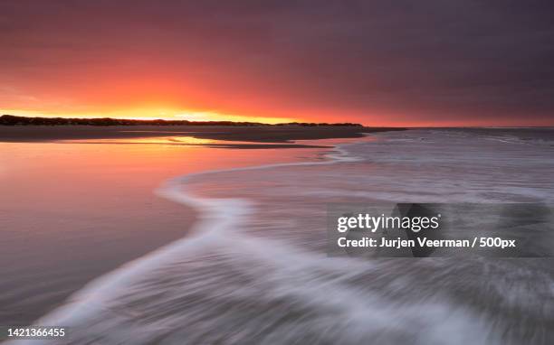 scenic view of sea against dramatic sky during sunset,terschelling,netherlands - natuurgebied stock-fotos und bilder